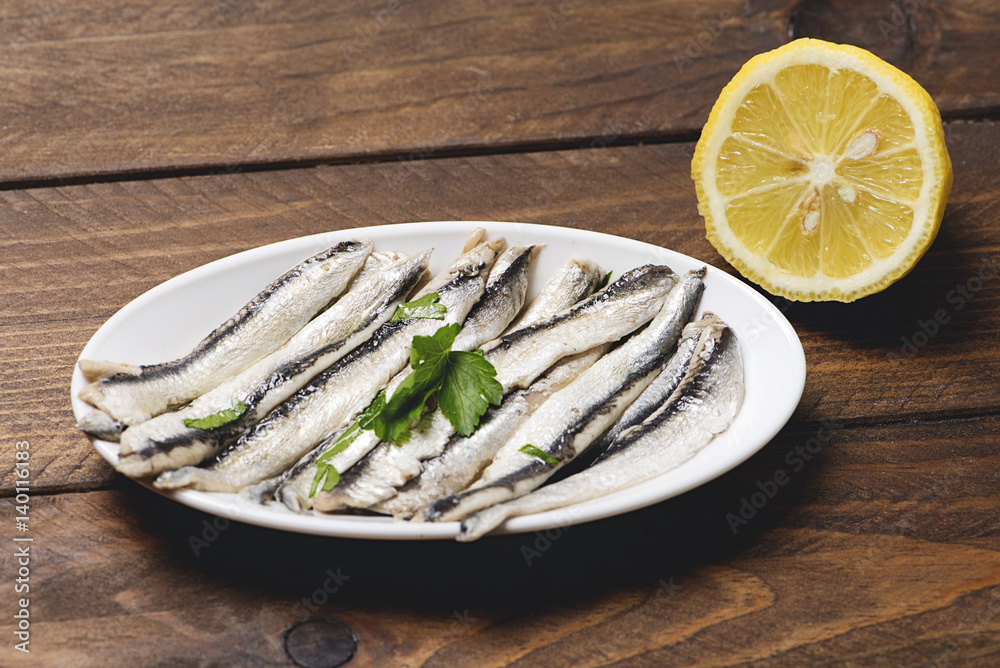 Plate of anchovies with olive oil, vinegar and lemon. Half lemon. Plate of anchovies with olive oil, vinegar and lemon. Half lemon.