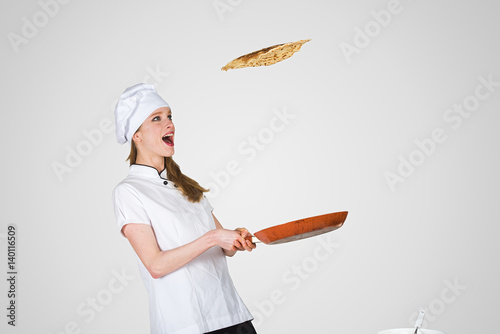 Fotografi female chef is flipping a crepe in the air using a frying pan