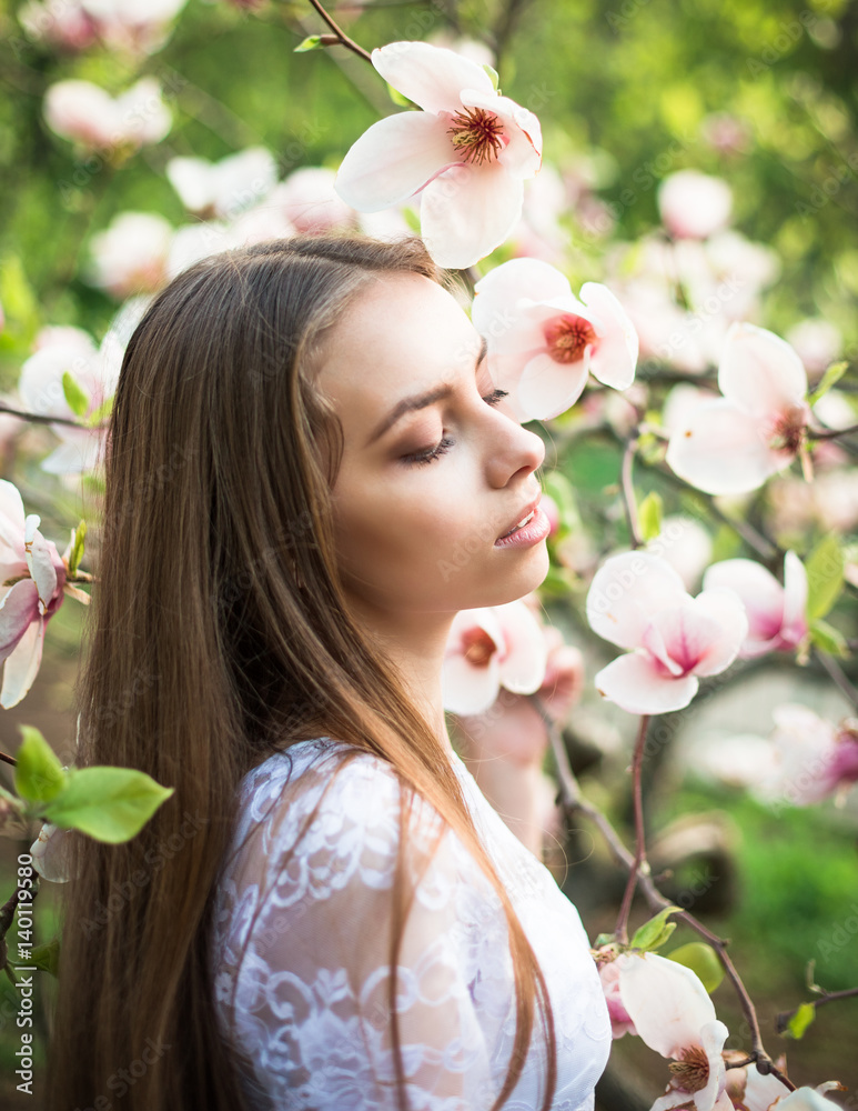 Fototapeta premium Young pretty girl relax in beautiful garden. Fantastic pink magnolias