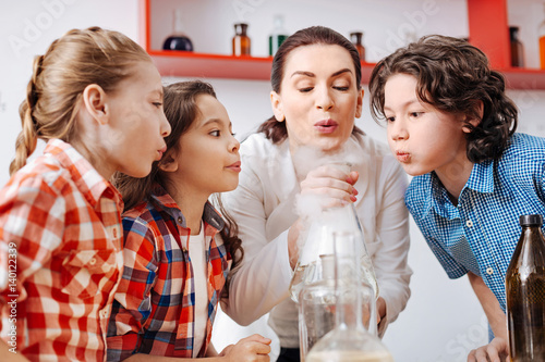 Positive nice children blowing on the chemical flask