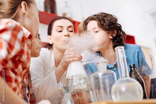 Cute curious boy blowing on the chemical flask