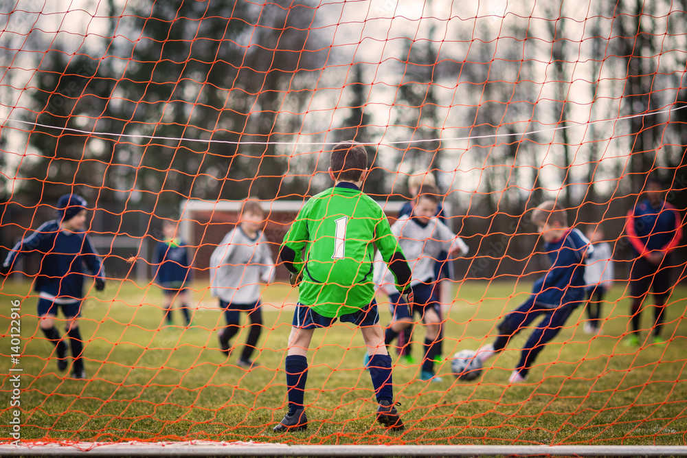 Obraz premium Young soccer goalie defending the net with forward player striking the ball in the background