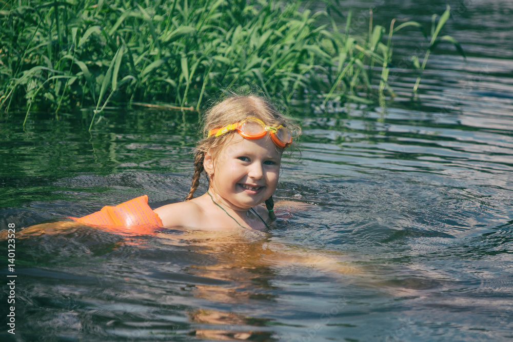 A child bathes in a summer river.