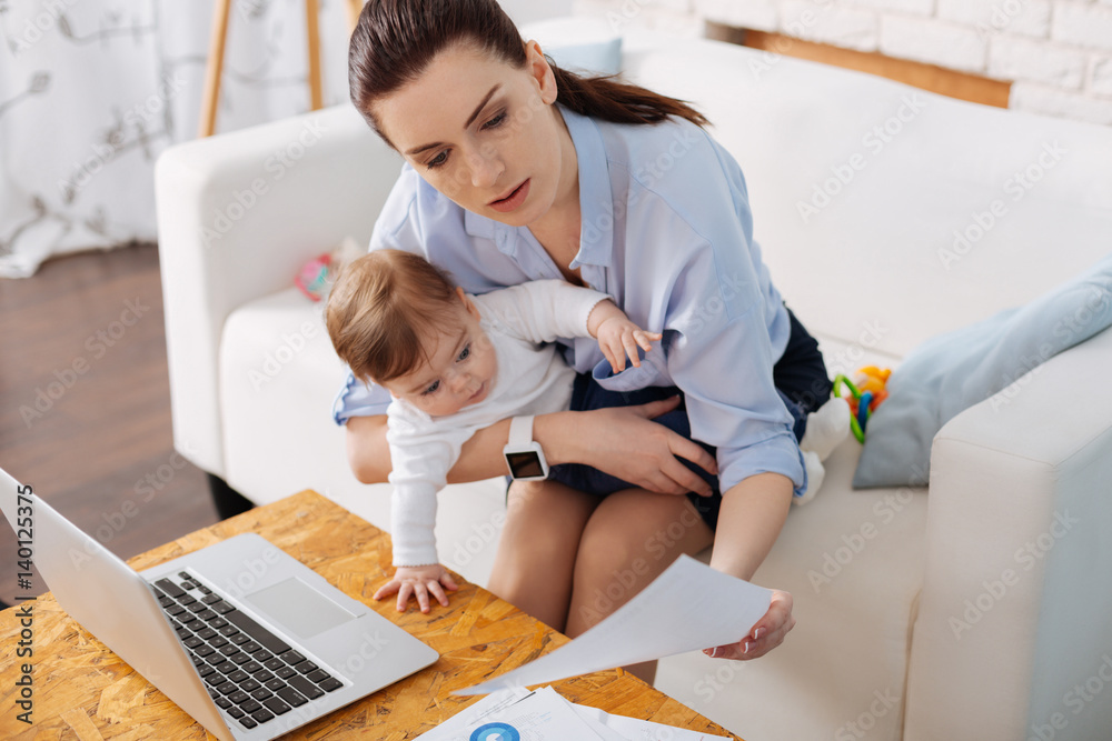 Adorable little girl looking interested in moms business - obrazy, fototapety, plakaty 