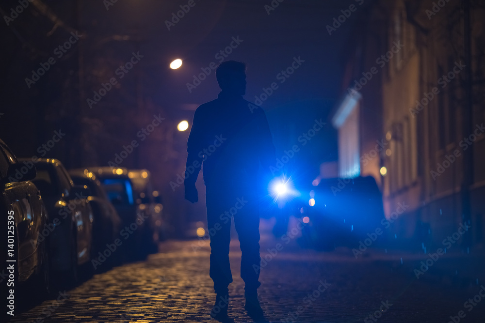 The man with a flashlight stand on wet road. Evening night time