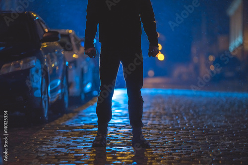 The man stand on the wet road. Evening night time. Telephoto lens shot © realstock1