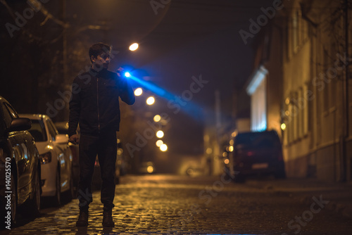 Fototapeta Naklejka Na Ścianę i Meble -  The man with a flashlight stand on the road. Evening night time