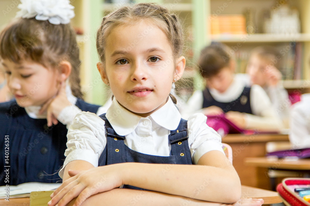 little beautiful schoolgirl in school uniform smiling happy sitting on desk little beautiful schoolgirl in school uniform smiling happy sitting on desk