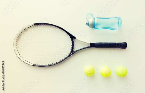 close up of tennis racket with balls and bottle