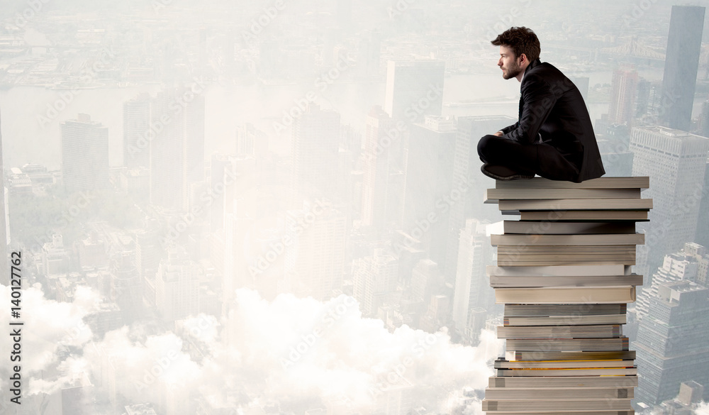 Student in city sitting on stack of books Student in city sitting on stack of books