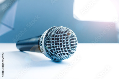 A microphone lying on a white table. Against the background of studio equipment, lighting. photo