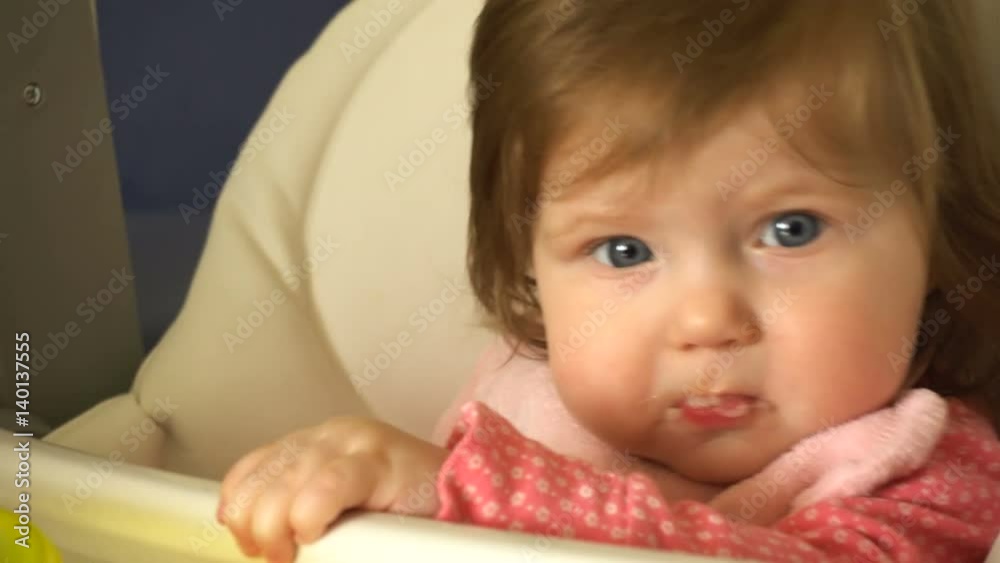 Baby sits at a children's little table and mom feeds her Baby sits at a children's little table and mom feeds her