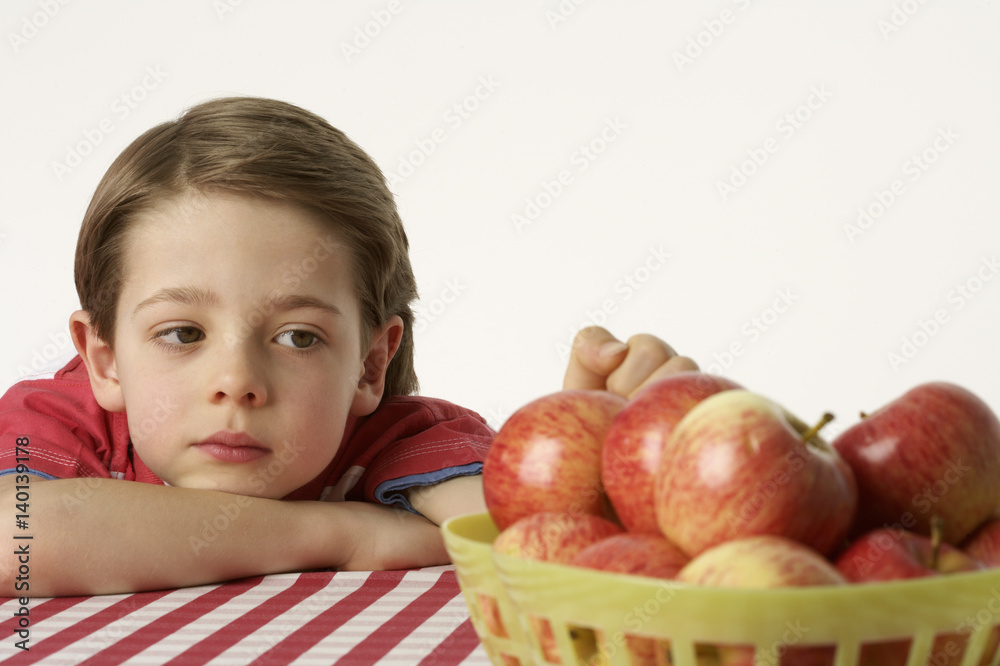 Fototapeta premium Boy sitting beside a few apples
