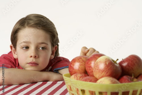 Boy sitting beside a few apples photo