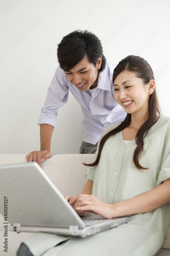 Young couple looking at laptop monitor, sitting on sofa Young couple looking at laptop monitor, sitting on sofa