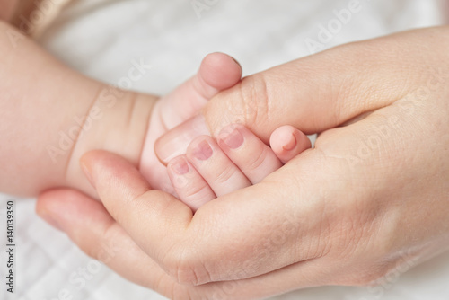 A newborn baby holding his mother's hand