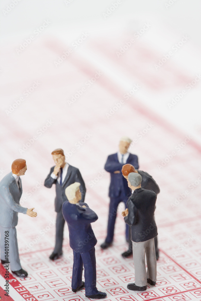 Group of businessmen figurines standing on a lottery ticket Group of businessmen figurines standing on a lottery ticket