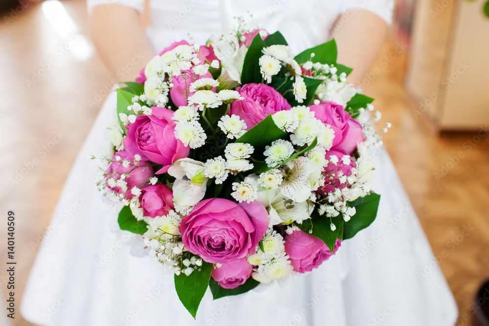 Bride holding beautiful wedding bouquet with pink roses, closeup