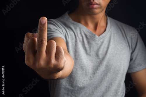 Man showing fuck off with the middle finger on black background.