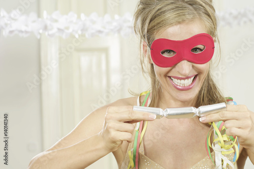 Woman with mask pulling on a Christmas cracker photo