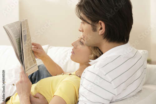 Young couple reading a newspaper together