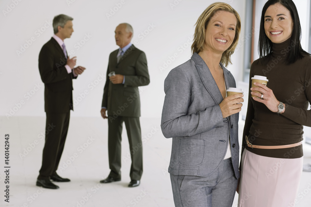Fototapeta premium Group of business men and women in an empty office, drinking from coffee mugs