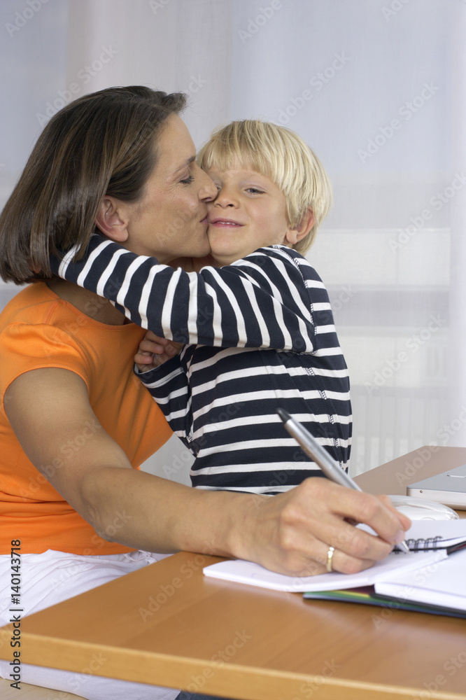 Mother taking notes while kissing her son (4-5 Years) Mother taking notes while kissing her son (4-5 Years)