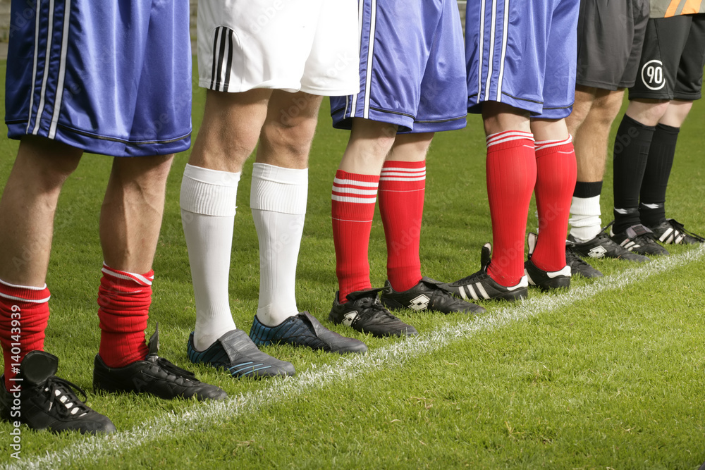 Six footballers in sports wear standing next to each other on a pitch whereas one of them is standing in the opposite direction (part of) Six footballers in sports wear standing next to each other on a pitch whereas one of them is standing in the opposite direction (part of)