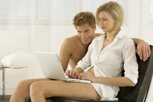 Couple using laptop, woman sitting on a chair