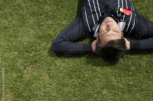 Relaxed referee lying on soccer field