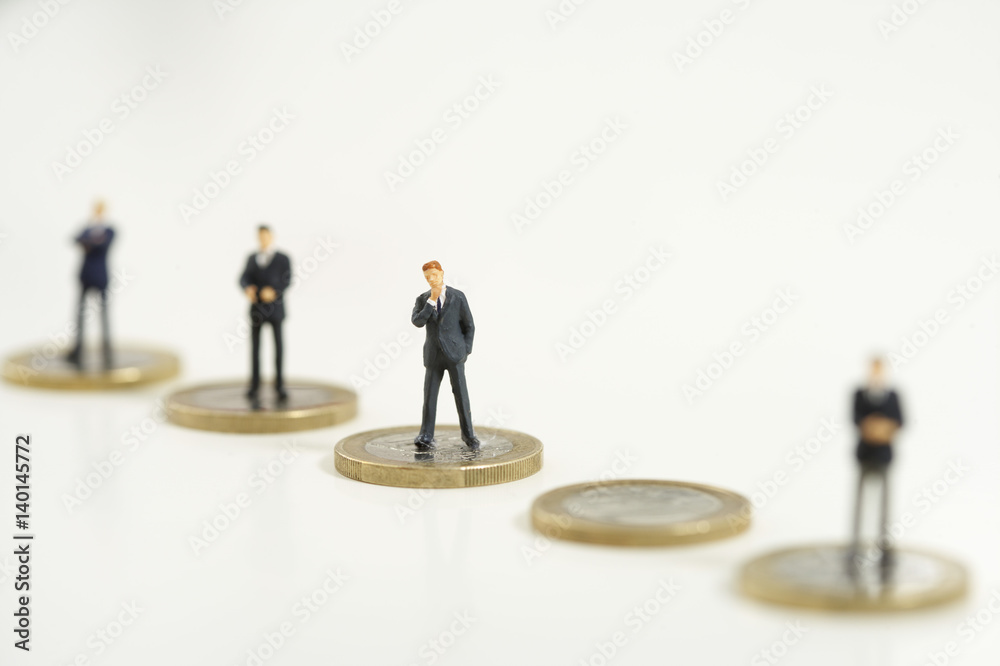 Businessmen figurines standing on one Euro coins Businessmen figurines standing on one Euro coins