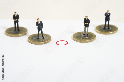 A red circle between businessmen figurines standing on Euro coins
