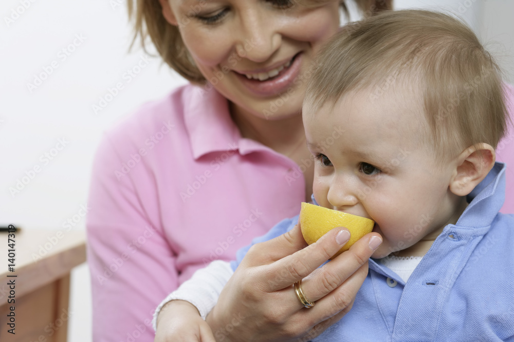 Mother feeding son with a lemon