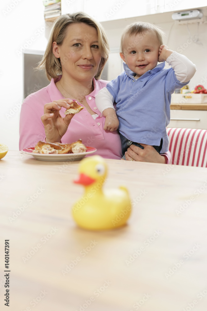 Fototapeta premium Mother feeding son, rubber duck in foreground