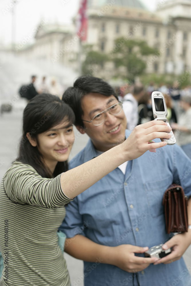 Asian woman is taking a picture of herself and an Asian man, selective focus Asian woman is taking a picture of herself and an Asian man, selective focus