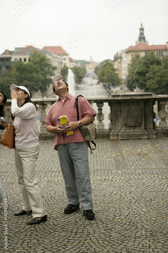 Three Asian people with cameras looking up, focus on foreground