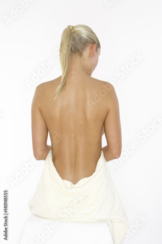 Blonde young woman wrapped in a towel  rear view