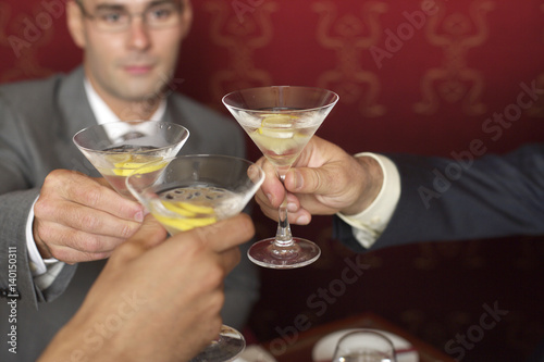 Three businessmen clinking glasses with cocktails