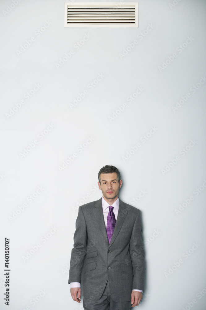 Businessman standing under air conditioner Businessman standing under air conditioner
