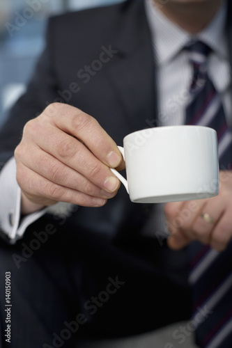 Businessman sitting and holding a cup of coffee in his hand