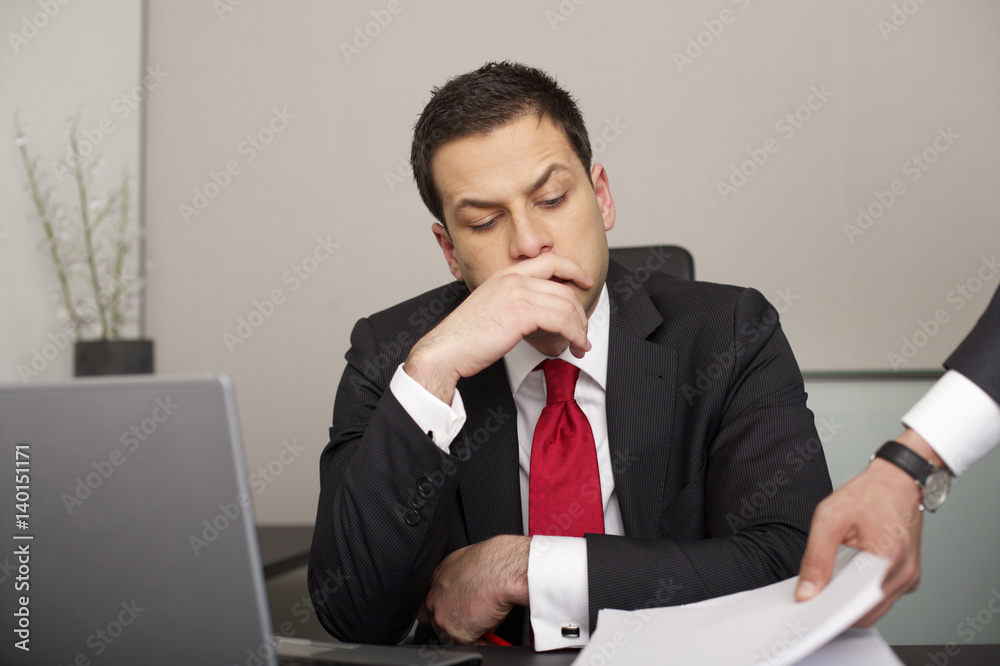 Stressed businessman looking at a stack of documents Stressed businessman looking at a stack of documents
