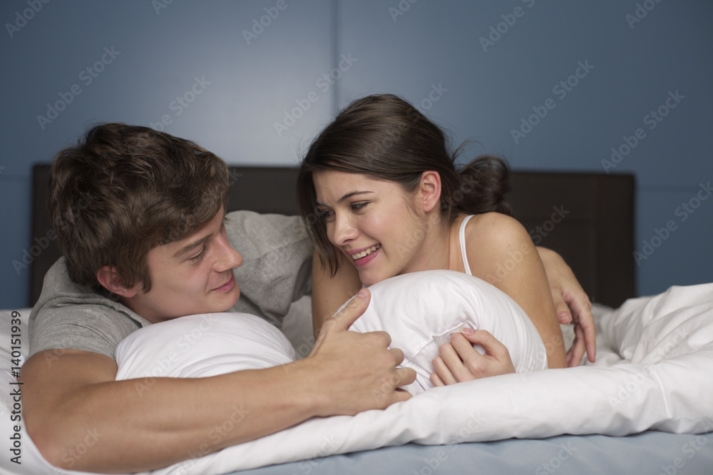 Young couple lying on front in bed, selective focus