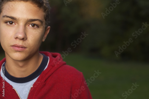 Teenage boy with brown hair in a park, close-up, selective focus