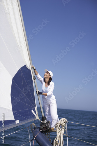 Woman standing at the railing on the bow of a sailboat