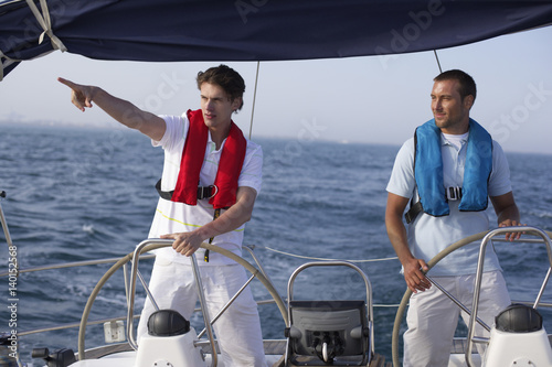 Two men steering a boat