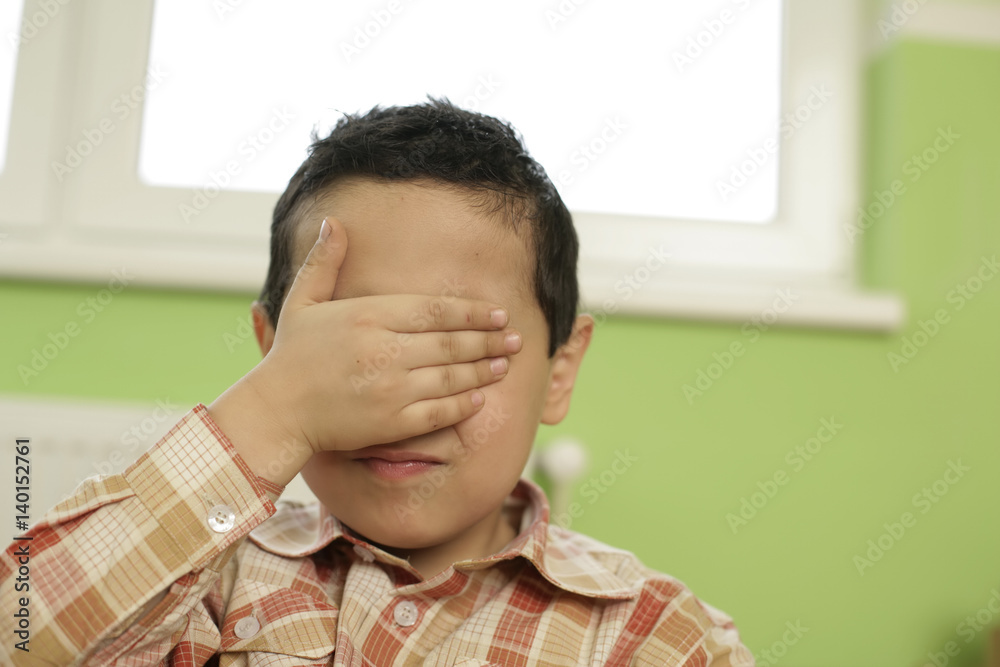 Boy covering his face Boy covering his face