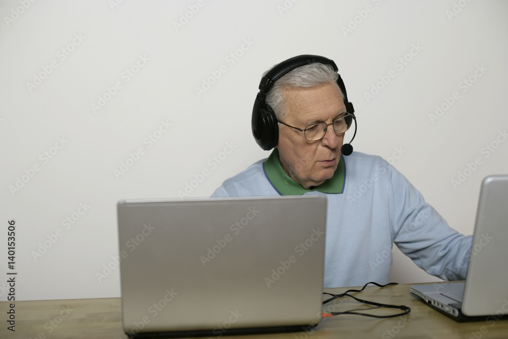 Senior man with headset using a laptop, fully_released Senior man with headset using a laptop, fully_released