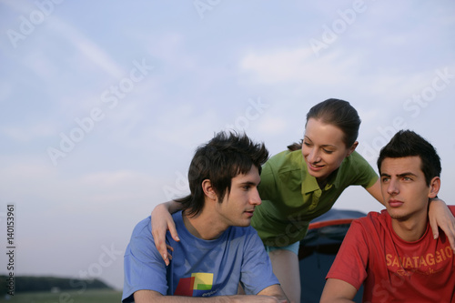 Young woman is resting her arms on two boys' shoulders