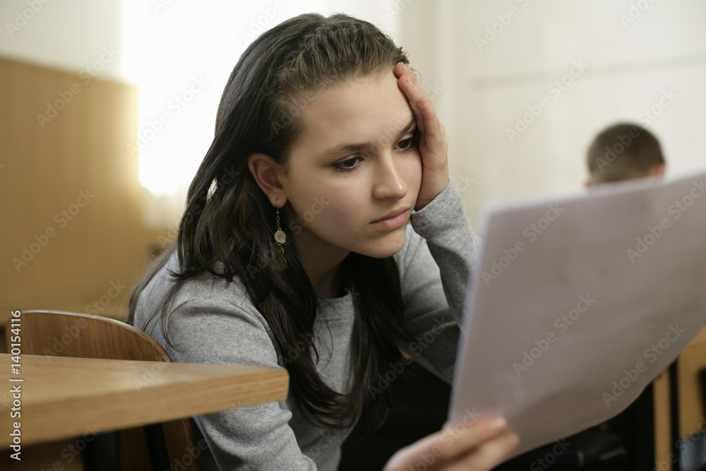 Distressed teenage girl holding an sheet of paper Distressed teenage girl holding an sheet of paper
