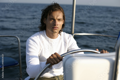 Man at a steering wheel of a sailboat